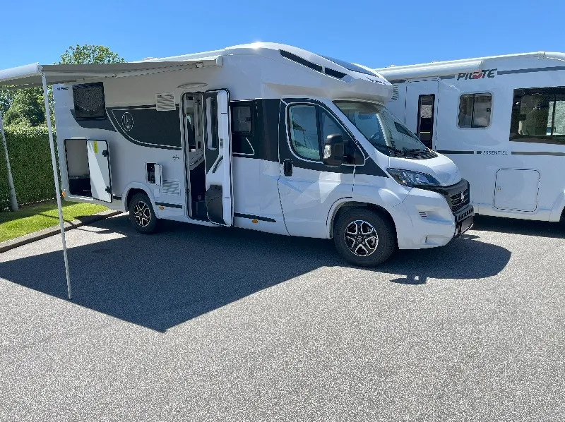 Autocamper med markise slået ud på parkeringsplads