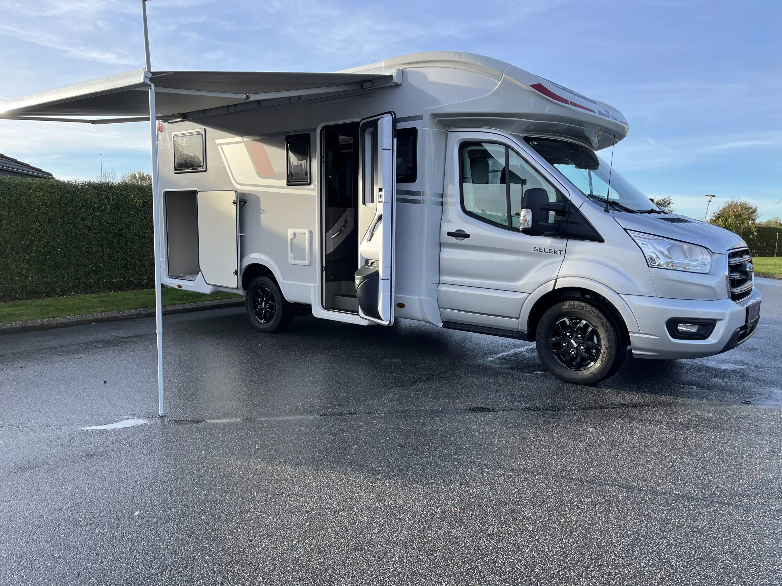 Hvid autocamper med udtrukket markise og åben dør