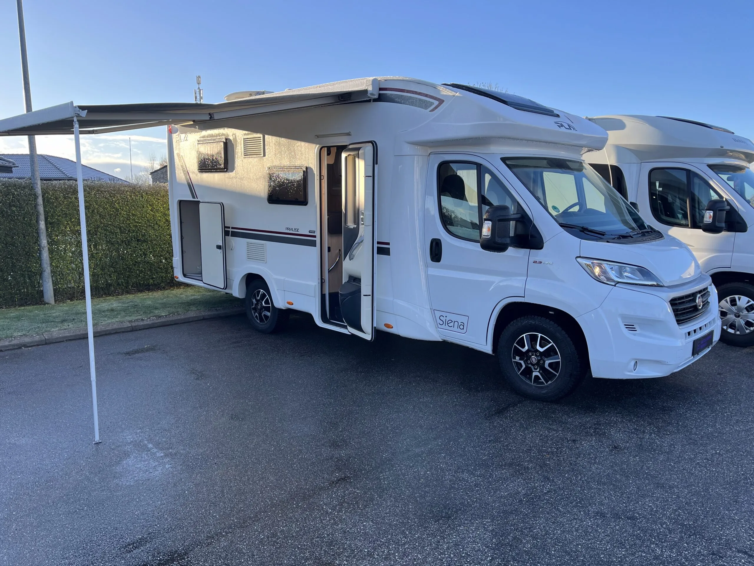 Hvid autocamper med markise slået ud