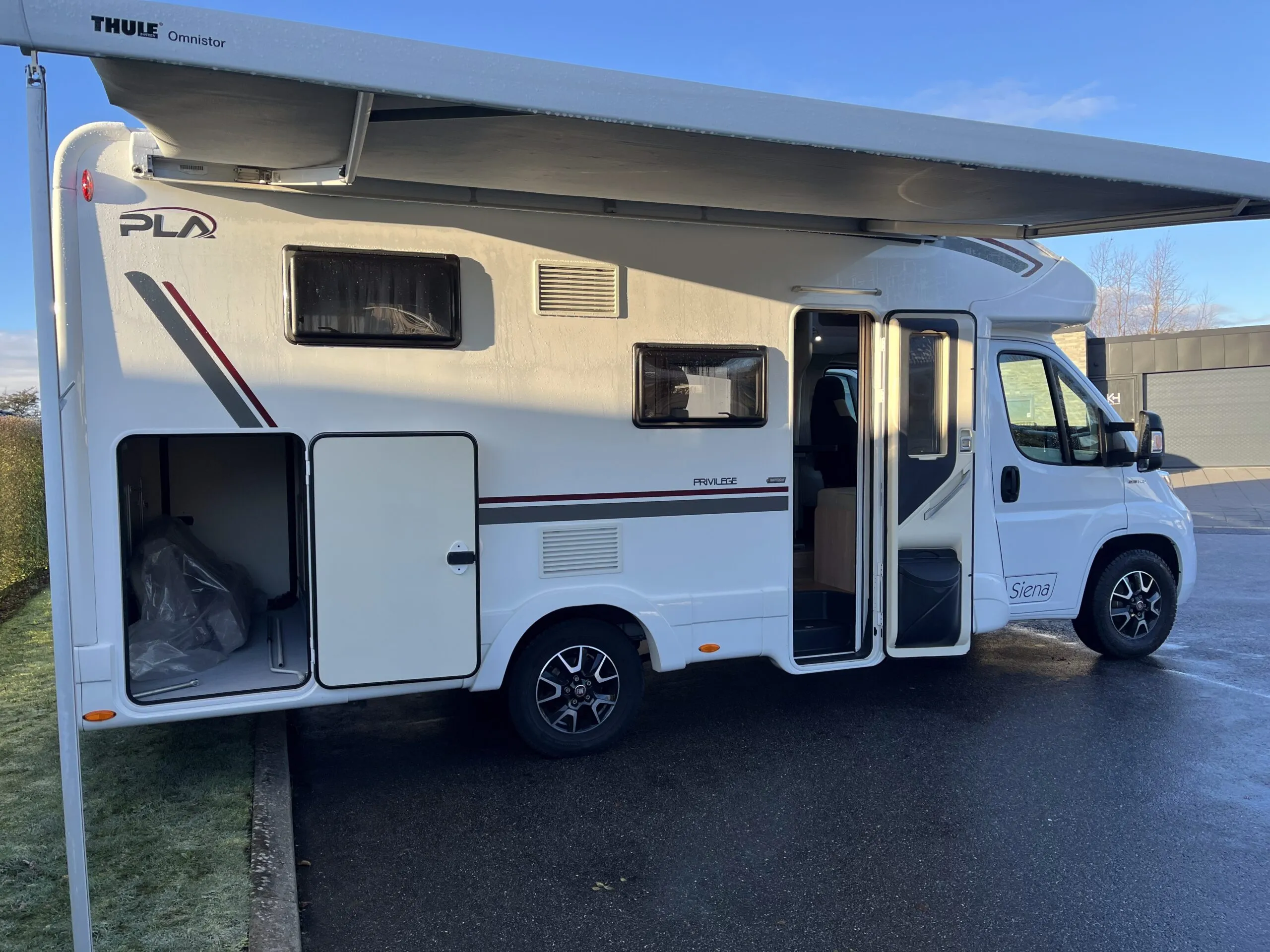 Hvid autocamper med markise og åben sidedør