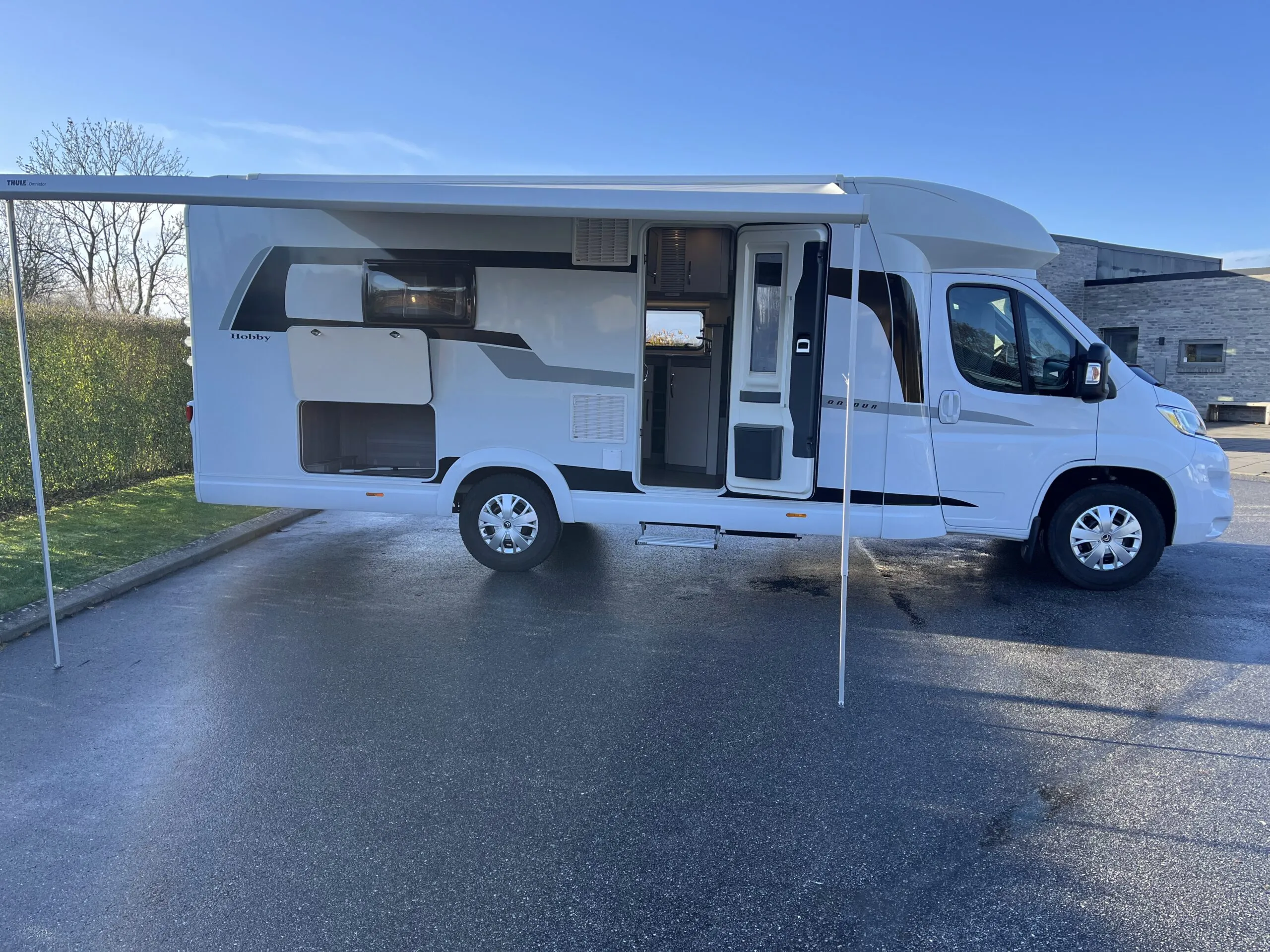 Hvid autocamper med markise parkeret udenfor