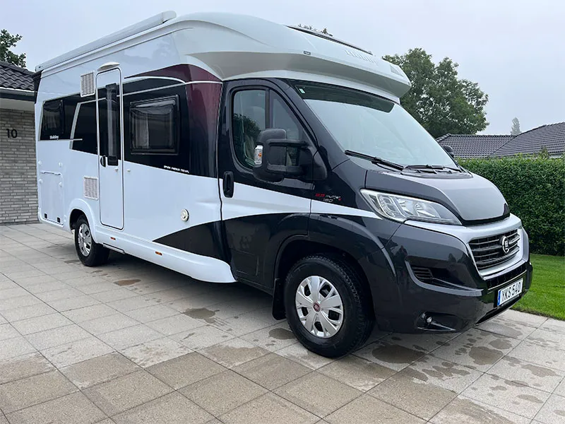 Sort og hvid autocamper parkeret ved hus